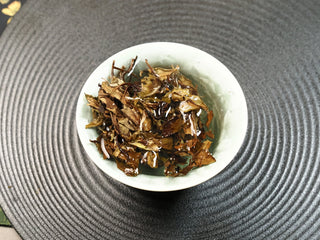 2021 Fuding Shou Mei leaves steeping in a gaiwan, partially unfurled in hot water with amber liquor developing.