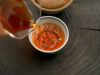 Pouring hot water into a cup of 2024 Bulang Mountain ripe pu-erh tea