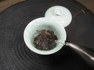 Pouring hot water into a celadon gaiwan to brew 2021 Dayi Guanchao Raw Puerh Tea Batch 2101.
