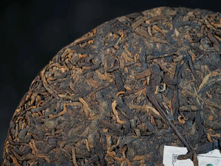 Close-up of the front surface of Bulang Mountain Ancient Tree Ripe Pu-erh tea cake, highlighting tight leaf compression and dark sheen