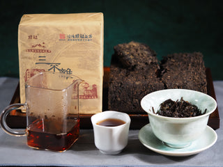 A complete tasting set of the 2018 Genshe "Three Essentials" Fu Brick Tea with dry brick, pitcher, and cup.
