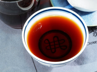 A cup of mellow Liubao tea with a rich ginseng aroma and deep burgundy color.