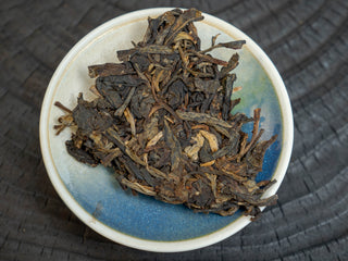 Pried loose leaves of 2006 Kaiyuan Reserve raw Puerh tea in a ceramic display dish for tea tasting.