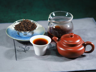 Full Puerh tea set including dry loose leaf, brewed liquor, and a Yixing teapot, perfect for a traditional Gongfu tea experience.
