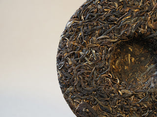 Center indentation and inner ticket detail on Mangfei Mountain sheng Pu-erh tea cake