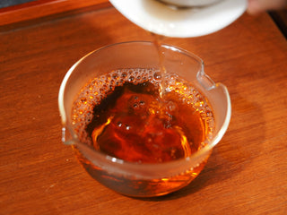 Pouring clear amber Jingyang Fuzhuan tea into a glass Gongdao Bei.