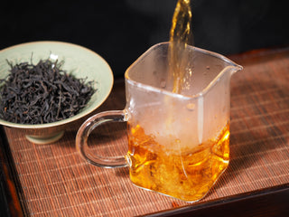 Pouring brewed Wild Wilderness Dianhong Black Tea into glass pitcher