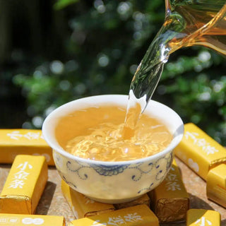 Pouring freshly brewed Silver Needle white tea into a traditional porcelain cup, surrounded by tea sticks.