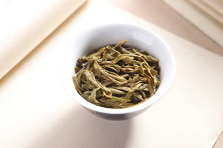 Wet tea leaves (Ye Di) in a white gaiwan, showing thick, tender, and elastic spring tea shoots from Lincang.