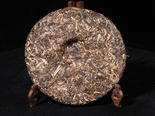 Back view of the stone-mold pressed raw Puerh cake with distinct traditional compression indent.