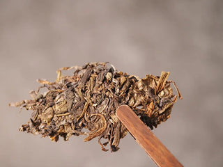 Close-up of a small loose chunk from Value Classic 2008 Tribute Sheng Pu-erh Tea Cake – 357g Menghai (2019 Pressed), showing rich leaf texture