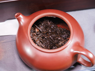 Wet fermented tea leaves of the 2019 Fu Brick inside a red clay teapot after the first infusion.
