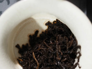 Close-up of the wet leaves from the Yunnan Mini Ripe Pu-erh Tea Brick in a gaiwan, showing the even fermented leaf texture and quality.