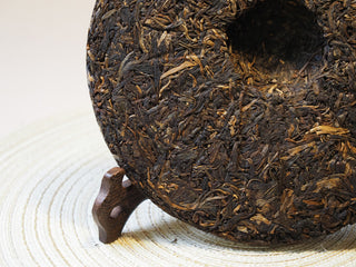 Side profile view illustrating the thickness and density of the 2005 Lincang raw Pu-erh tea cake.