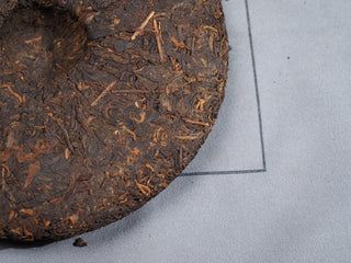 Back side of unwrapped 2006 Dayi 7572 ripe Puerh tea cake showing center dimple compression