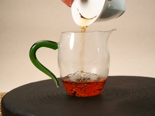 2013 Fuding Shou Mei tea poured from a gaiwan into a glass pitcher, the liquor pouring in a deep reddish amber stream.