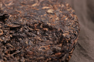 Bottom edge of the 2019 Bojun 500g cake, showing the tightly pressed dark fermented leaves with golden tips.