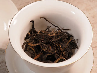 A portion of 2019 Qilin Tribute Sheng Pu-erh Tea Cake – Ancient Arbor 357g placed inside a traditional white porcelain gaiwan for brewing.