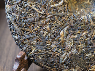 Close-up of robust leaves and golden-brown hues on the edge of the raw puerh tea cake.
