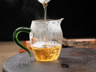 Bright golden-yellow brewed tea soup of 2021 Dayi Guanchao Raw Puerh Tea in a glass fair cup (gongdao bei).
