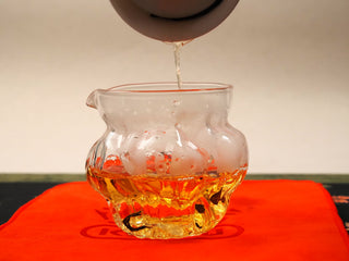Deep golden tea liquor from 2024 Fuding Shou Mei and Chen Pi waffle cake being poured into a glass fairness pitcher.