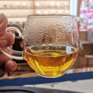 Rich golden tea liquor of 2006 Mangbo raw Pu-erh poured into a glass fairness cup.