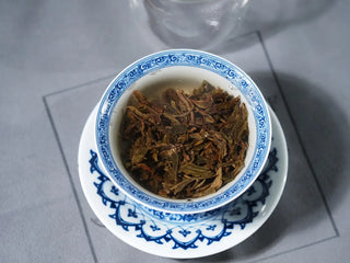 Ancient Arbor Harmony Raw Pu-erh Tea leaves fully steeped in clear golden liquor inside the gaiwan.