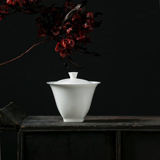 Artistic display of Tian Yuan Di Fang white porcelain gaiwan against dark background
