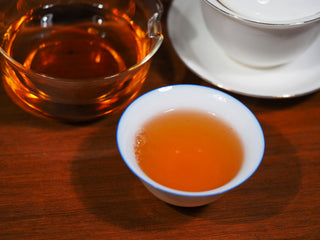 Bright amber liquor color of 2014 Vintage Jingyang Dark Tea in a tasting cup.