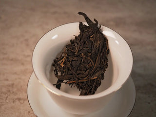 Loose leaves of 2019 Lincang Ancient Arbor Sheng Pu-erh Tea Cake placed in a porcelain gaiwan ready for brewing