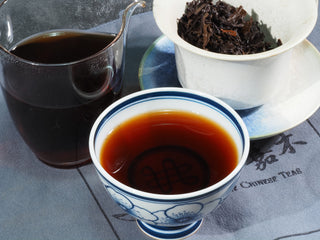 Traditional Liubao tea ceremony set including gaiwan, glass pitcher, and brewed tea.