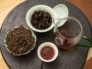 Complete tea session display showing dry leaves, wet leaves in gaiwan, and brewed shou puerh tea liquor.