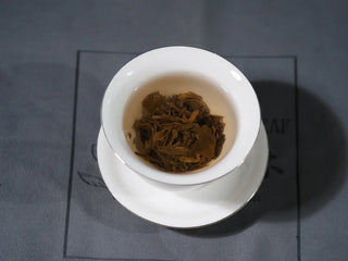 Mengku TeaSoul Sheng Pu-erh Coin Tea blooming in gaiwan, releasing golden liquor and honey aroma
