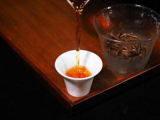 Pouring brewed Fengqing Golden Snail Dianhong Black Tea into cup