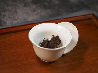 Small piece of Qilin Hao Fengshan Gushu Ripe Pu-erh Tea Cake 2021 placed in a Gaiwan ready for brewing