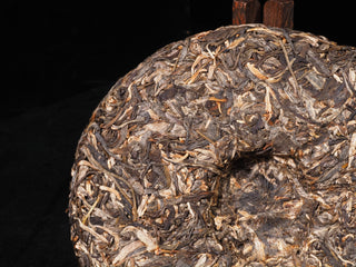 Close-up detail of the traditional stone mold compression on a 2023 raw Puerh tea cake.