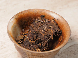 Value Classic 2008 Tribute Sheng Pu-erh Tea Cake – 357g Menghai (2019 Pressed) placed in a traditional white porcelain gaiwan before brewing
