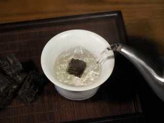 Brewing a piece of Yunnan Raw Pu-erh Waffle Cake – Three Legendary Leaves in a gaiwan with hot water