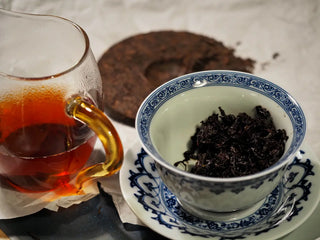 Yunnan Red Glow Ripe Pu-erh Tea Mini Cake – 100g brewed tea shown in a glass fair cup beside the gaiwan, highlighting the vivid wine-red liquor and infused leaves.