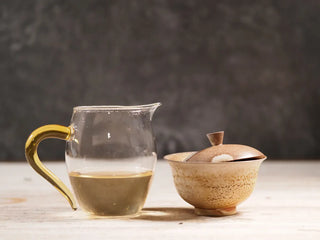 Snow Mountain Rare Wild Ancient Tree Sheng Pu-erh (2016–2023) – 100g Mini Cake, gaiwan and fair cup (cha gong) placed side by side, displaying bright golden-yellow tea liquor