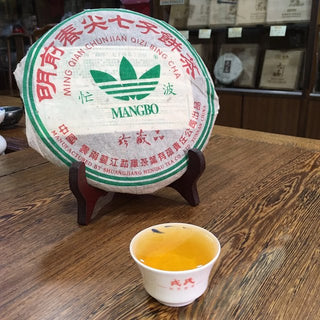 Professional display of 2006 Mengku Rongshi Mangbo raw Pu-erh cake and brewed tea.