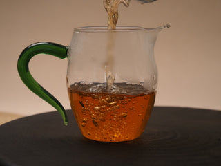 Golden brown tea liquor of 2019 Dayi 8542 raw puerh tea in a glass pitcher