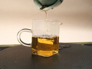 Clear deep amber tea liquor from Fortune 2021 Shou Mei mini cake displayed in a glass fairness pitcher.