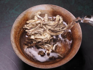 Hot water being poured over 2023 Jinggu Silver Needle White Tea buds in a gaiwan