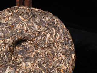 Macro shot of early spring raw Puerh tea leaves on the edge of a handcrafted Bulang Puerh cake.