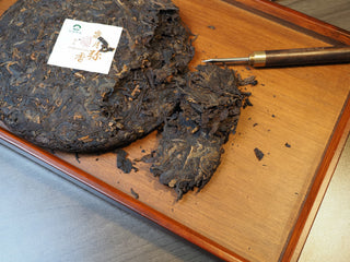 Prying loose leaves from the 2005 Lincang Shou Pu-erh tea cake using a traditional tea needle