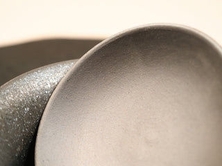 Texture contrast on wood-fired stoneware gaiwan from Dehua Fujian, rough dark exterior glaze against smooth light interior.