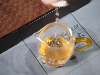 Pouring brewed Yunnan Raw Pu-erh Waffle Cake – Three Legendary Leaves tea from gaiwan into a gongdao cup