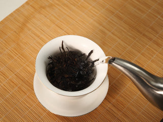 Kettle pouring boiling water over Jing Chang Hao Mengsong Autumn Harvest 2013 raw Pu-erh leaves in a gaiwan for the rinse