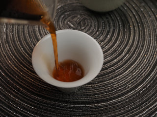 Pouring 2018 Dayi V93 ripe puerh tea infusion into a tasting cup